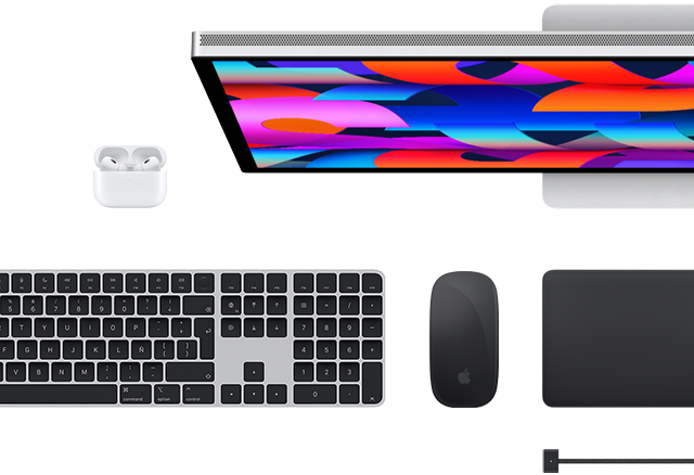 Vista desde arriba de algunos accesorios para el Mac: Studio Display, Magic Keyboard, Magic Mouse, Magic Trackpad, AirPods y cable de carga MagSafe